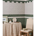 A cream-colored upholstered chair with wooden legs and nailhead trim featured in Seaton Ceramic sea cabbage design