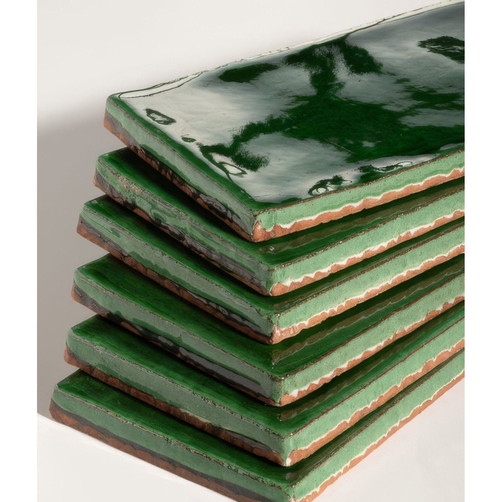 Stack of seaton ceramic sea grass green glazed tiles with rustic edges and glossy finish