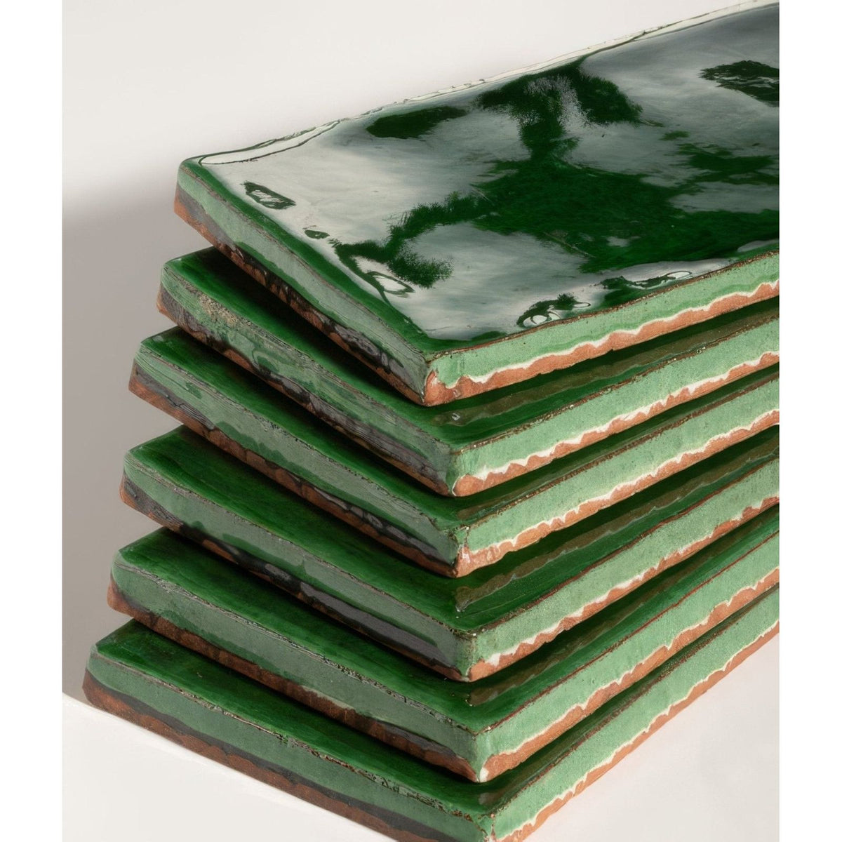 Stack of seaton ceramic sea grass green glazed tiles with rustic edges and glossy finish