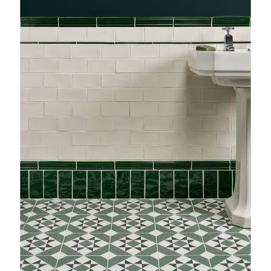 Seaton ceramic sea grass features white subway tiles with dark green borders and geometric gray black patterned floor tiles