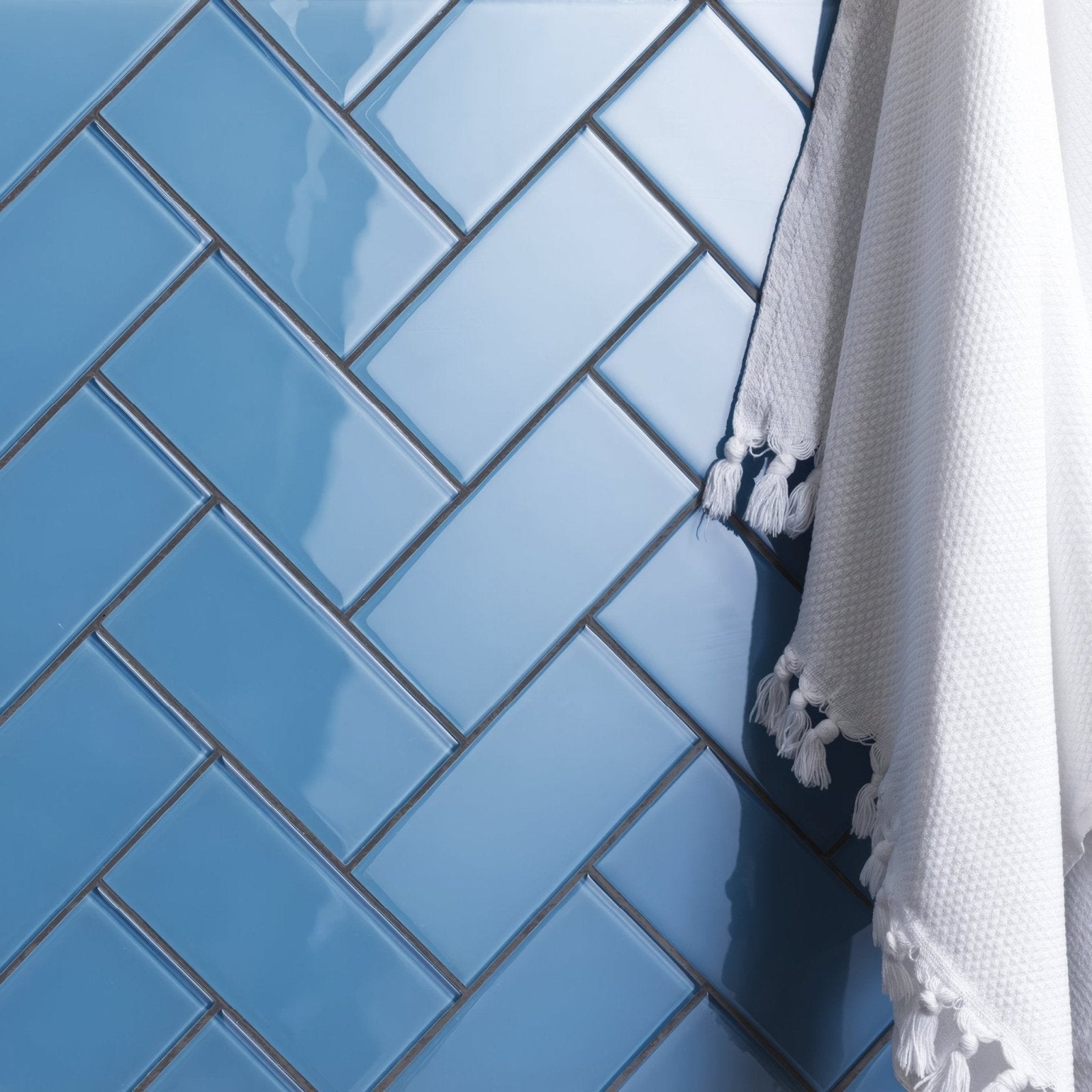 Seine clear glass brick featuring blue glossy subway tiles arranged in a herringbone pattern