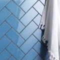 Seine clear glass brick featuring blue glossy subway tiles arranged in a herringbone pattern