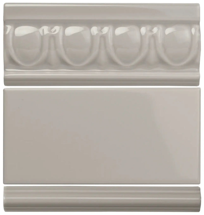 Set of three gray ceramic tiles featuring a decorative molded border tile, a plain rectangular wall tile, and a simple baseboard tile.
