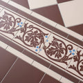 Shaftesbury 2 tile border brown on white ceramic tiles with intricate leafy patterns and blue dot accents
