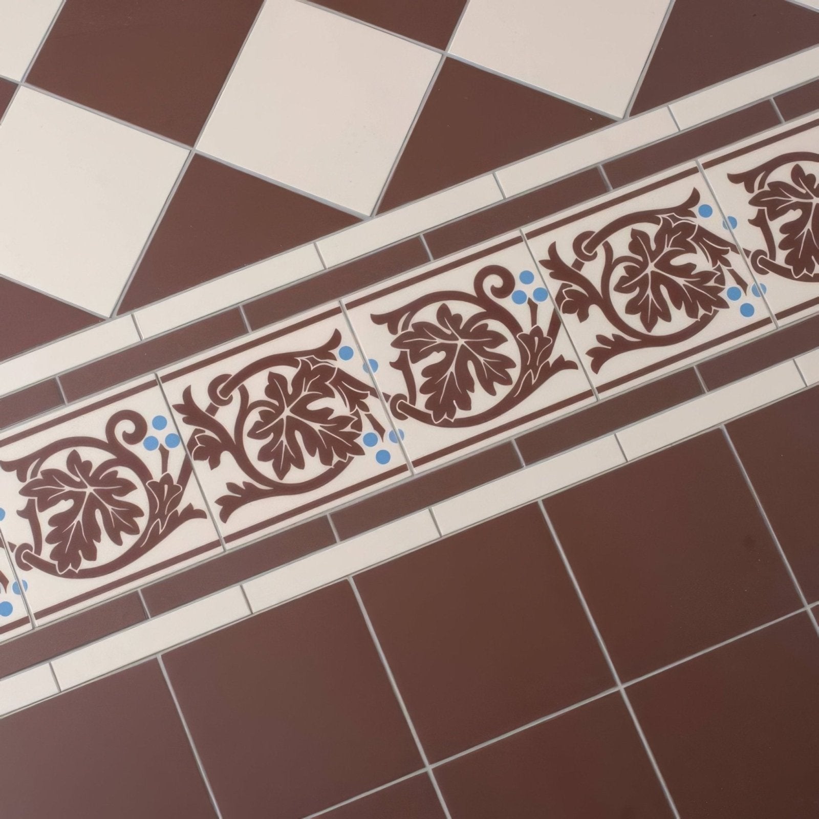 Brown and white ceramic tile border with intricate leaf patterns and blue accents shaftesbury 2 design