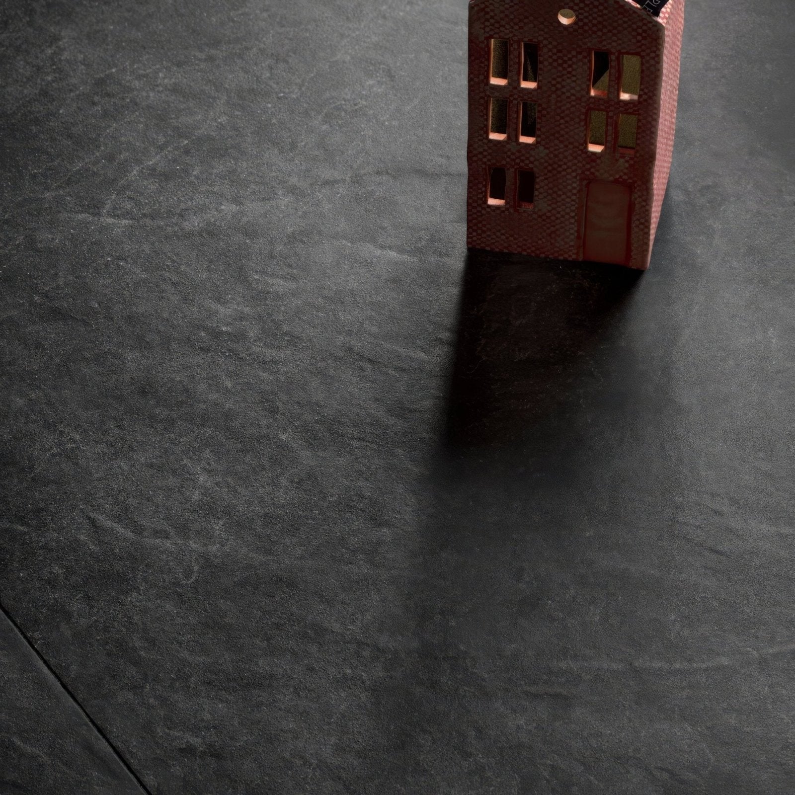A miniature red brick house model with detailed windows and textured surface showcasing shale black 60 x 120cm tile