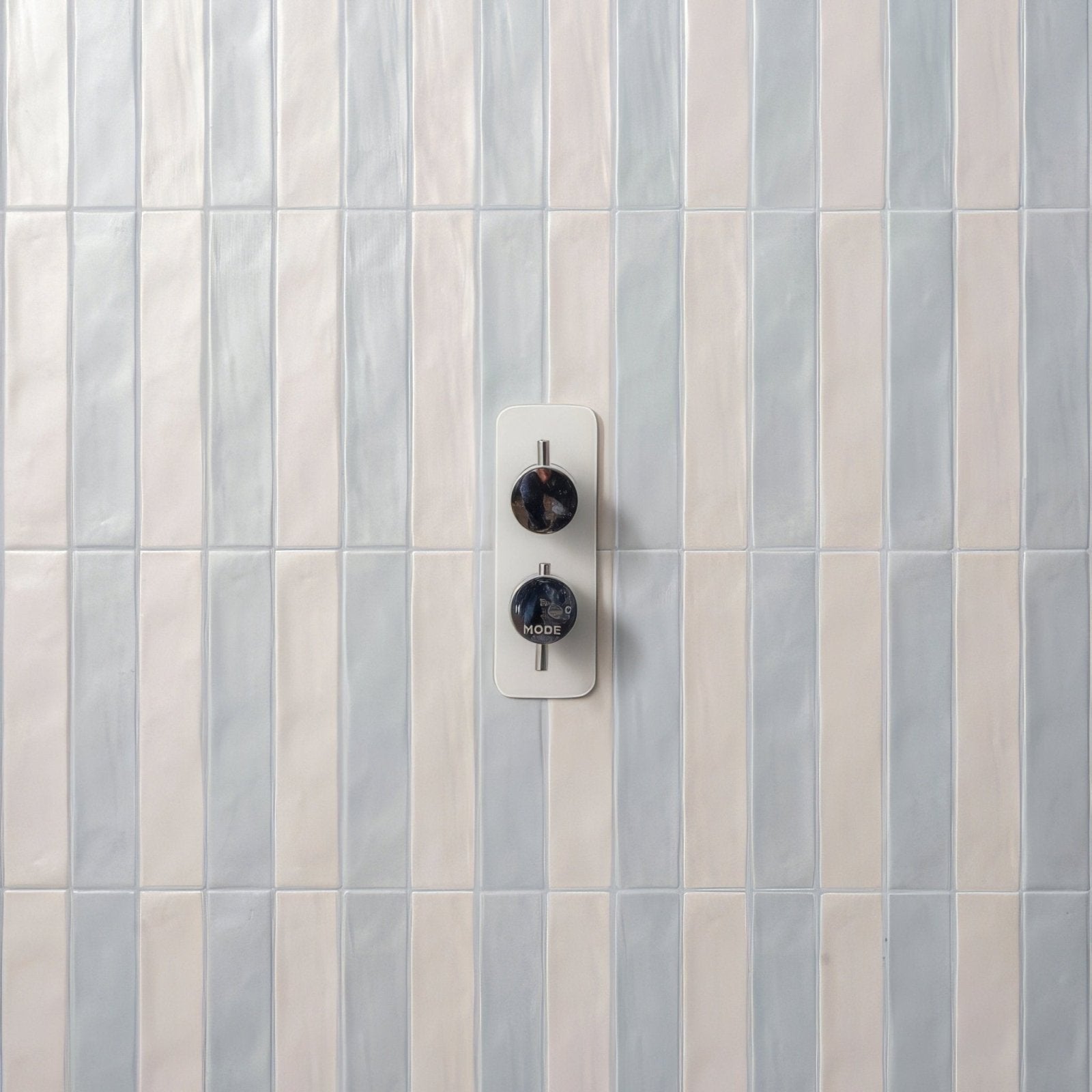 Modern white wall-mounted shower mixer with two black circular knobs in sherbet white brick 5x25cm design