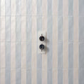 Modern white wall-mounted shower mixer with two black circular knobs in sherbet white brick 5x25cm design