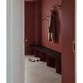 Golden ornate wall-mounted coat rack with a beige coat hanging from it in sherborne porcelain light finish