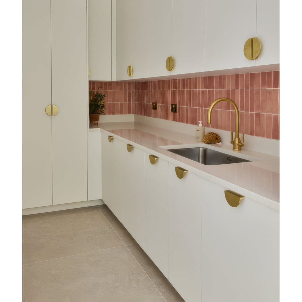 White sherborne porcelain light kitchen cabinets with gold semi-circular handles and matching gold faucet above sink