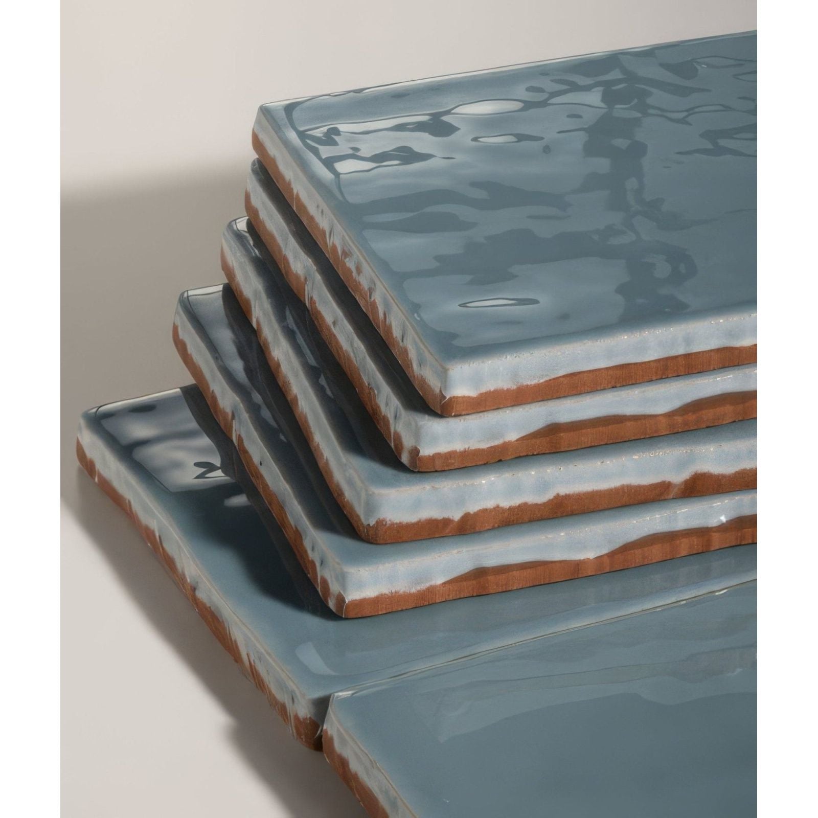 Stacked square ceramic shoreline shallow water tiles with matte blue glaze and exposed terracotta edges