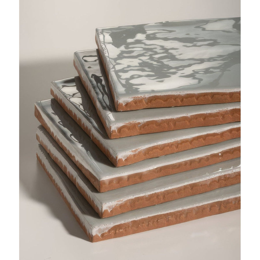 Stack of shoreline ceramic shingle tiles with gray and white marbled glaze and exposed terracotta edges