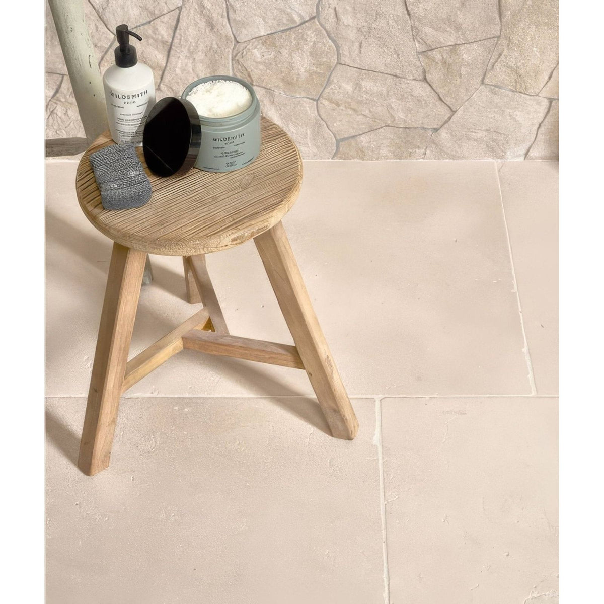 Light wood round stool with three angled legs and natural grain finish in sierra porcelain textured style
