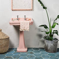 Pink ceramic pedestal sink with chrome faucets from the signature porcelain verdigris collection