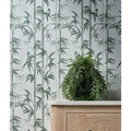 A lush silk screen ceramic lantau bamboo smoke green plant in a sleek black pot on a light wood cabinet