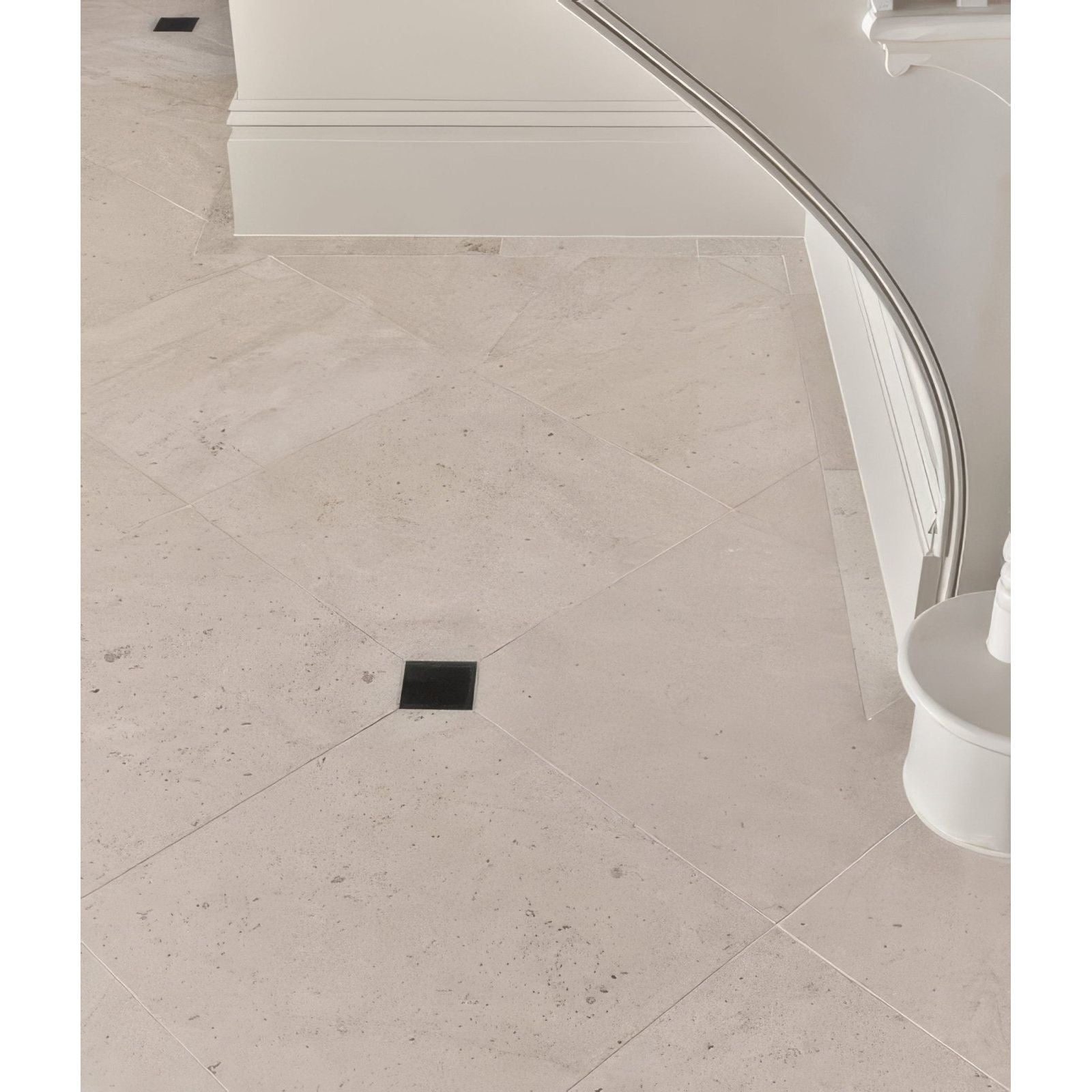 Beige sloane limestone honed finish stone tiles with subtle speckled texture in herringbone pattern with black accent tile