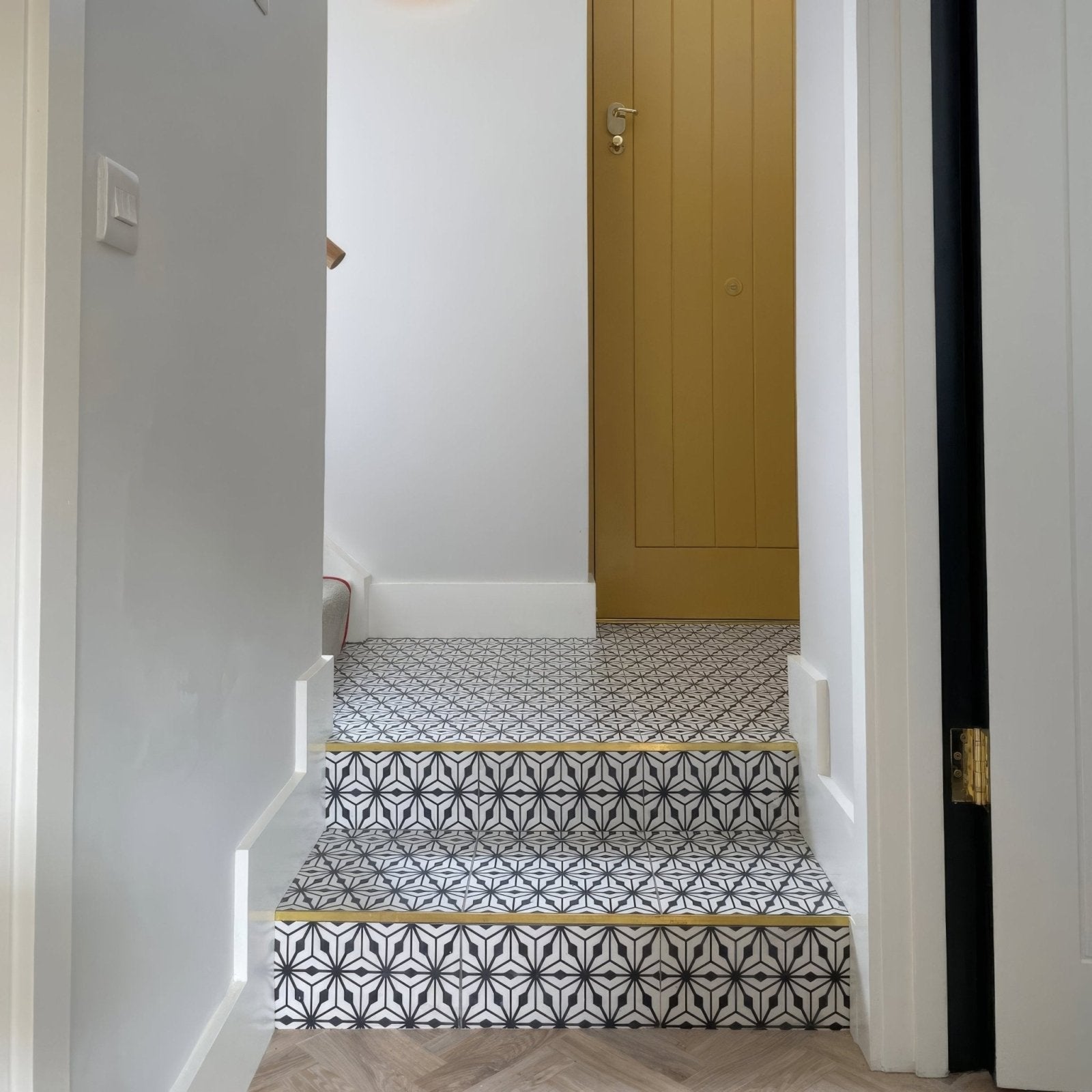 Black and white geometric patterned sorrento nizza porcelain tile stairs with gold-colored edges