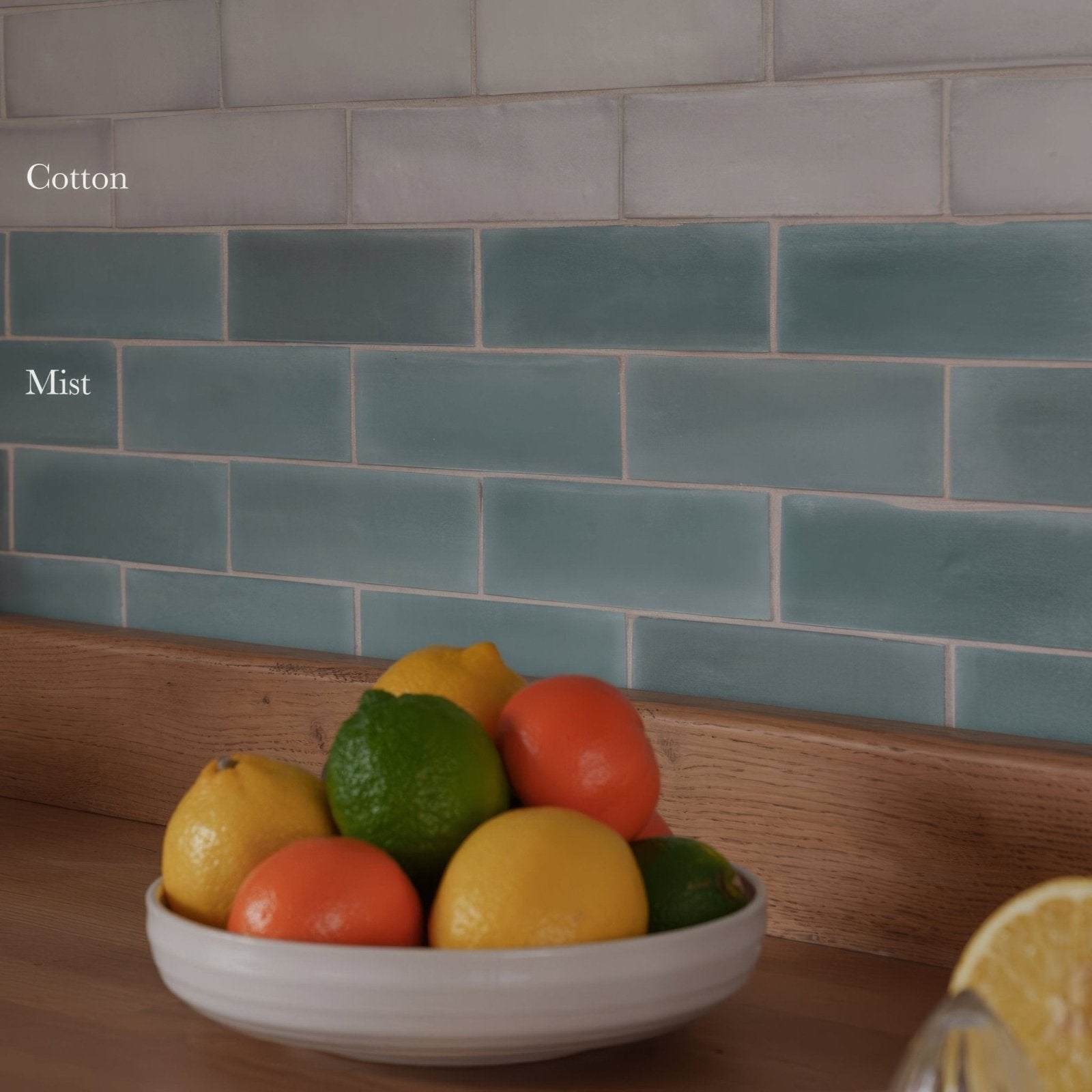 A white ceramic bowl filled with colorful citrus fruits on south cliff cotton brick tile background