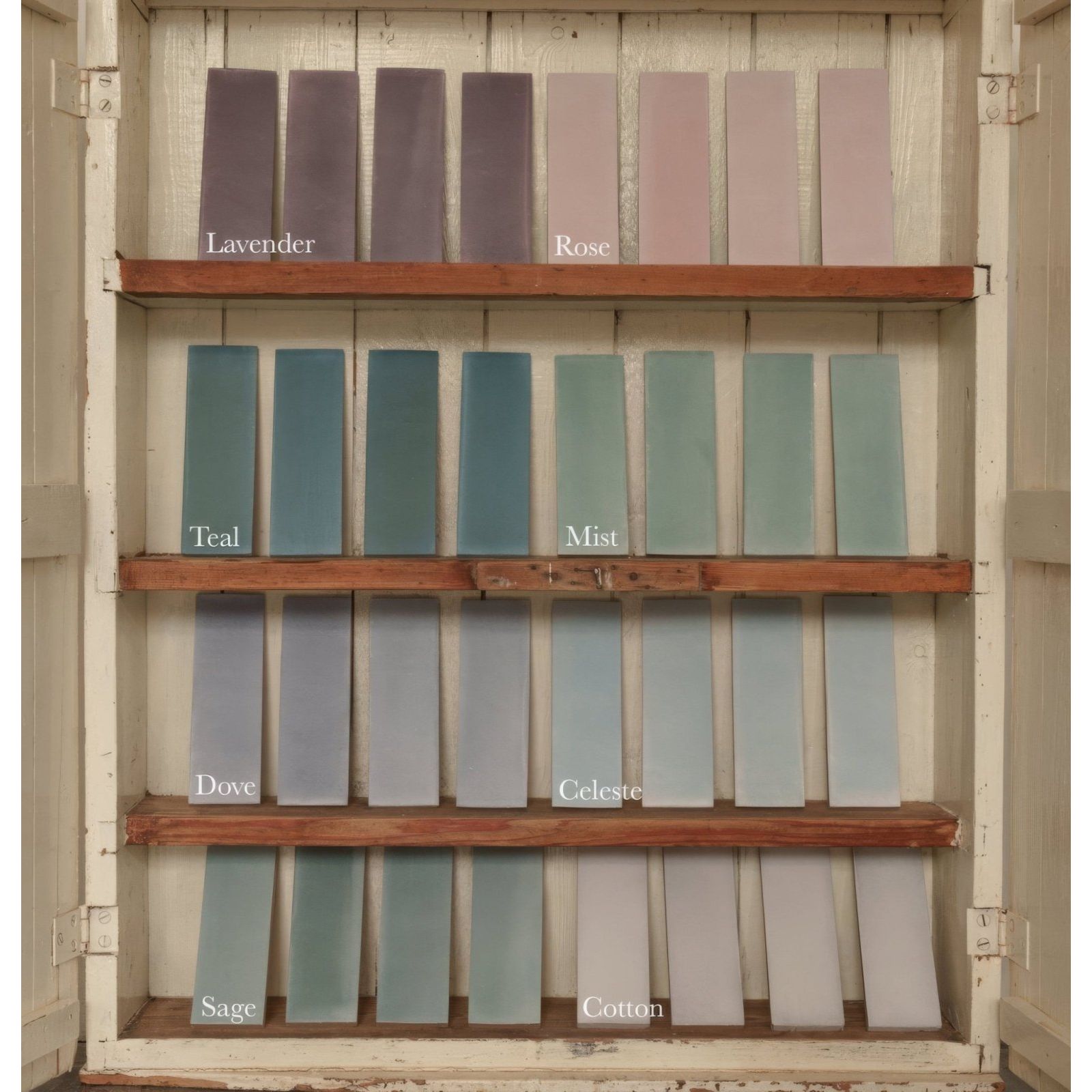 A collection of rectangular paint swatches in soft pastel shades displayed on wooden shelves for south cliff rose brick tile