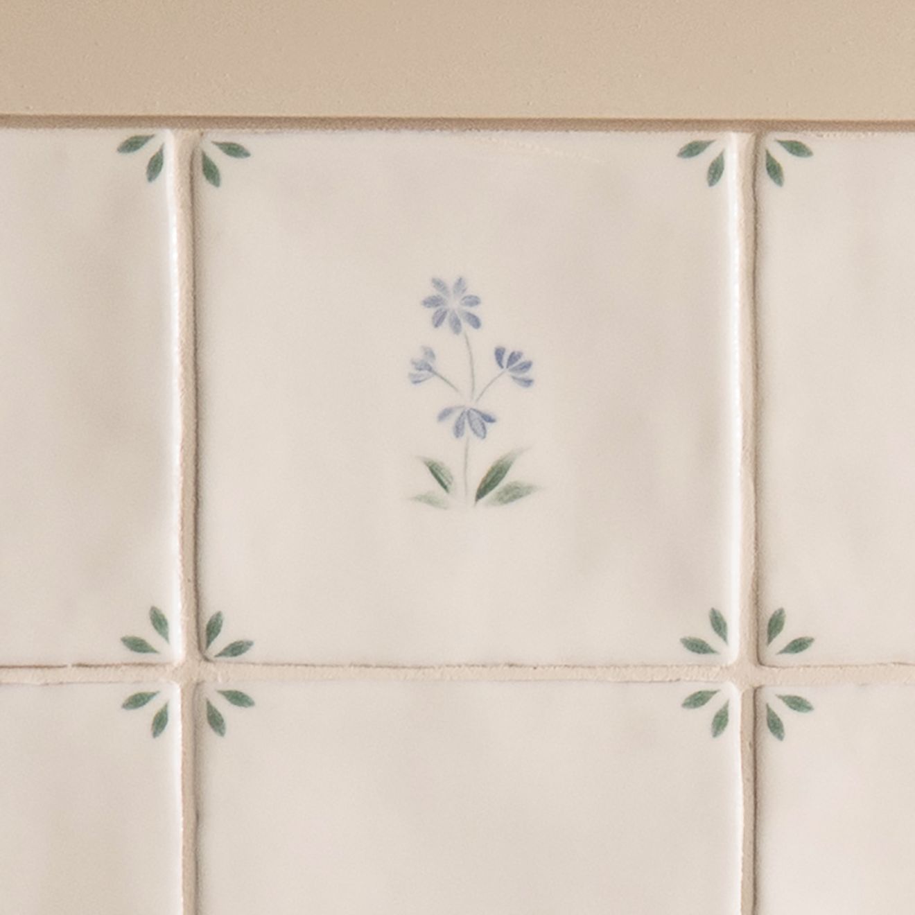 Off-white ceramic spring alice tiles 13 x 13cm with delicate hand-painted blue and green floral motifs