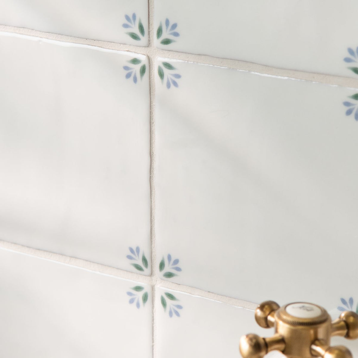 White ceramic spring april cornflower tiles 13 x 13cm with delicate blue and green leaf motifs at corners