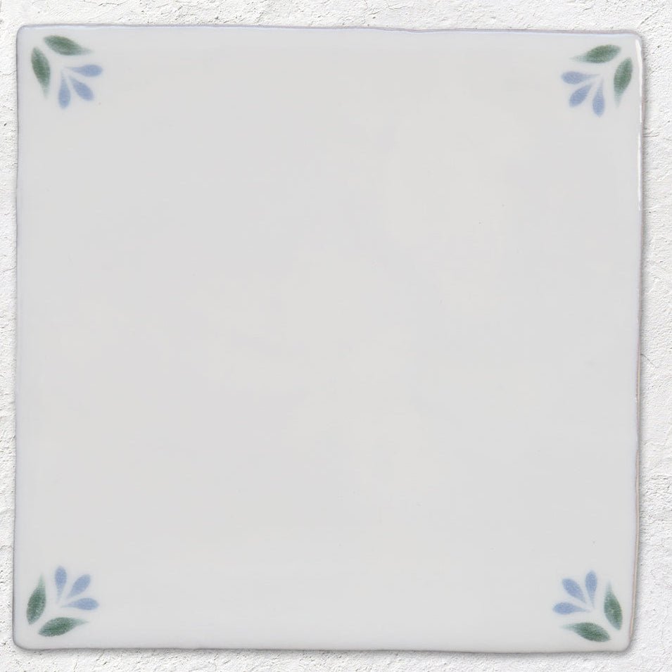 White ceramic tile spring april cornflower 13 x 13cm with delicate blue and green leaf motifs at each corner
