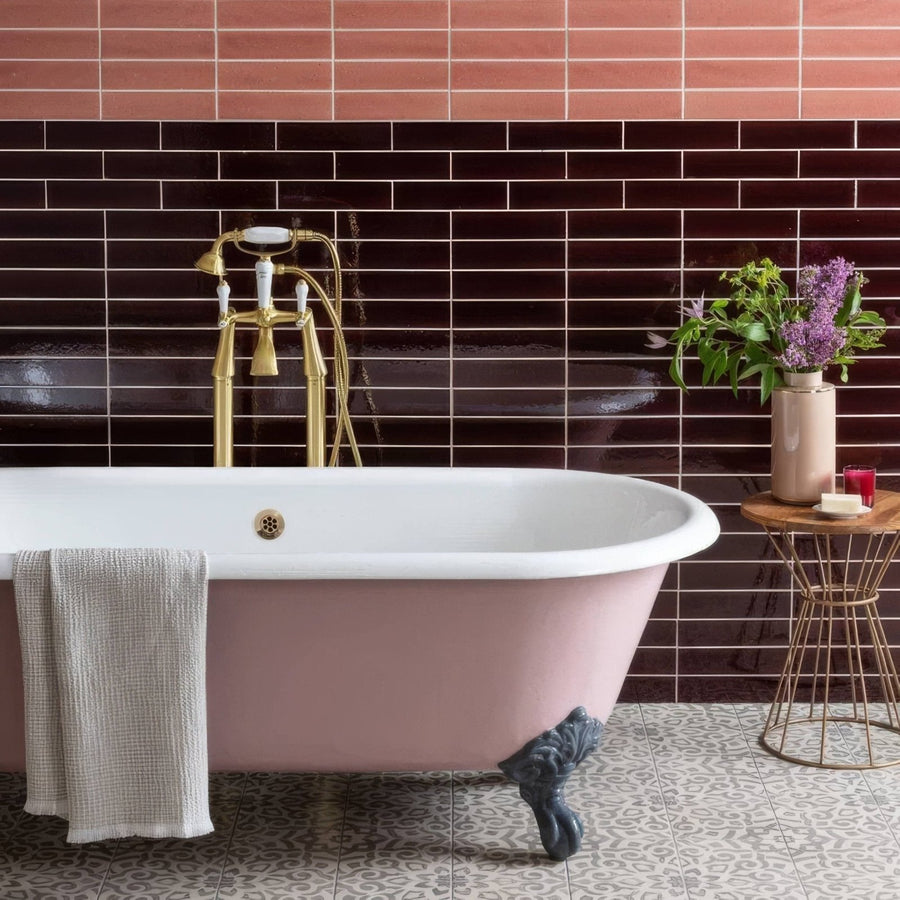 A pink clawfoot bathtub with a white porcelain rim and gold-toned fixtures featured with spring brick tile