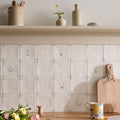 Off-white ceramic spring Lucie 13 x 13cm tiles with delicate gray floral and starburst patterns arranged in a grid
