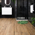 Green leaf-shaped bath mat with white vein detailing in springwood honey tiles for bathroom use