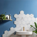 Statuario nuovo honed hexagon mosaic features white marble-effect tiles with gray veining for a backsplash behind sink
