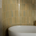 Beige and muted green glossy stone glaze ceramic chambray gloss brick tiles lining a curved wall above a white bathtub