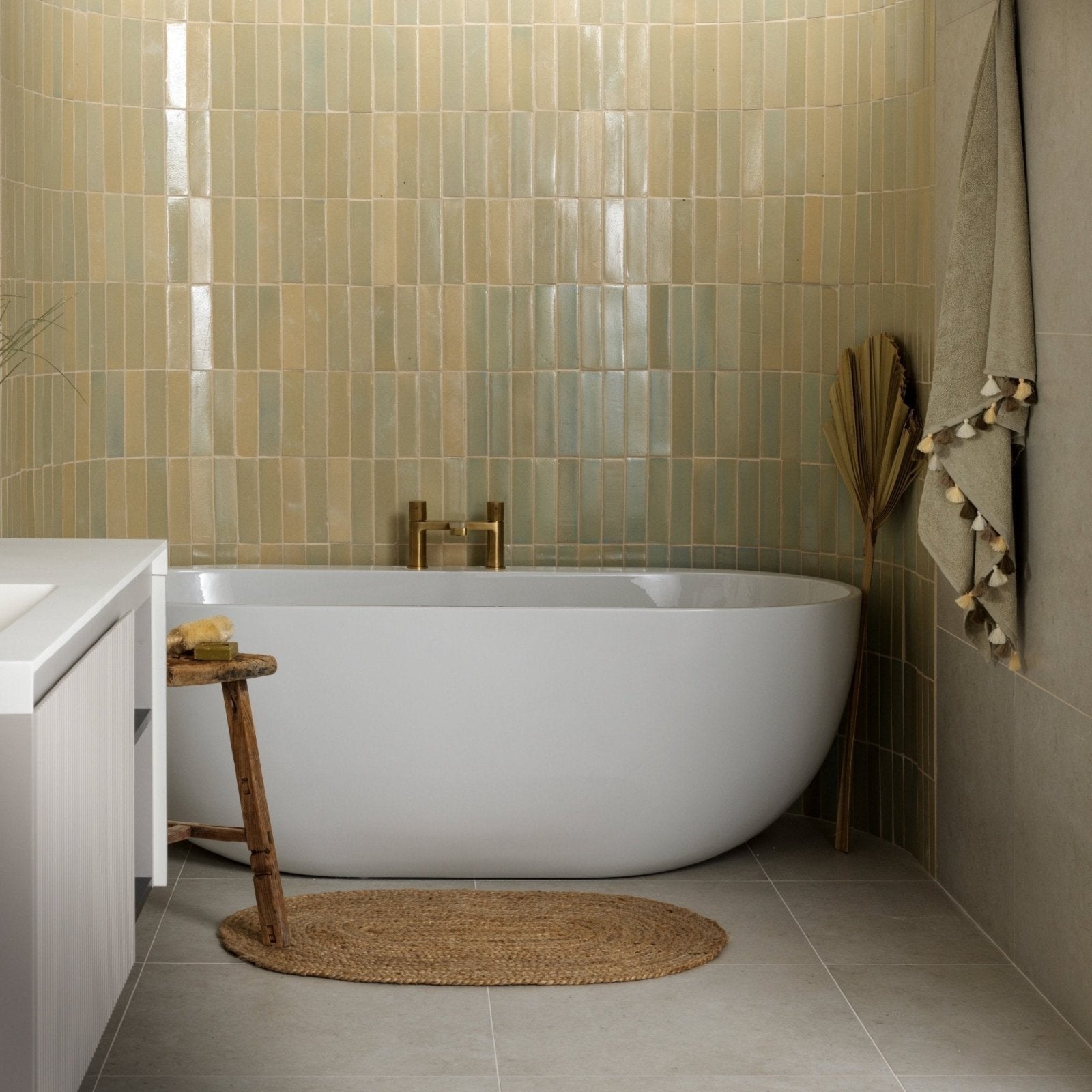 Modern freestanding white ceramic bathtub with sleek oval design and gold-toned faucet in stone glaze chambray gloss brick