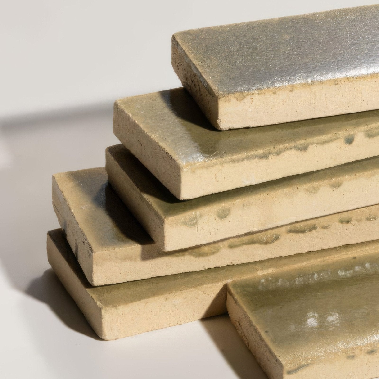 Stack of stone glaze ceramic lemongrass gloss brick tiles with matte beige bodies and glossy silver tops