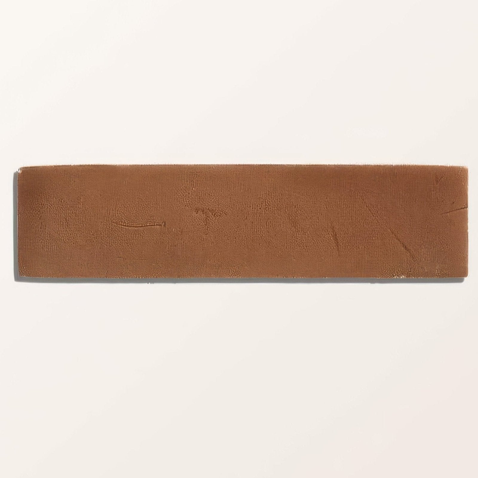 A rectangular brown leather headband with textured surface and subtle wear paired with stone glaze ceramic tan gloss brick