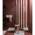 A stucco porcelain textured red ceramic sink with a white finish and black faucet mounted on a dark brown wall