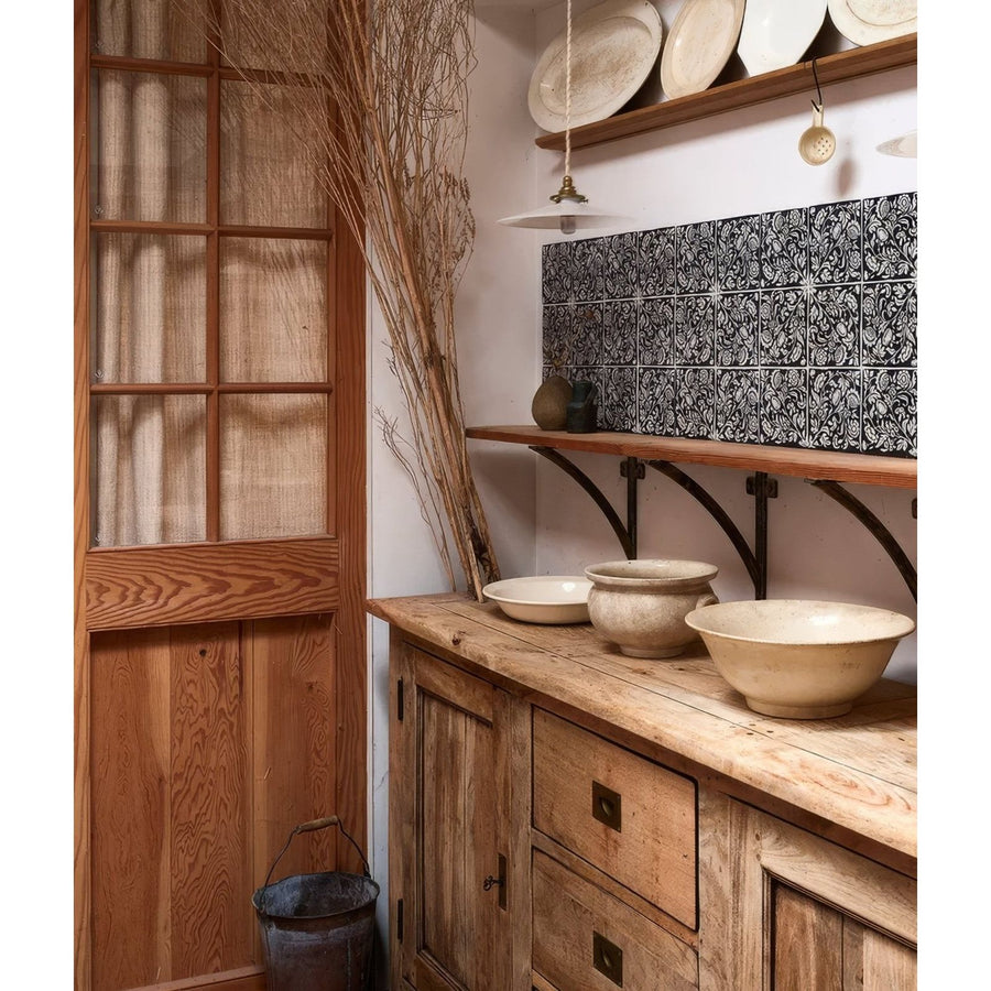 Rustic wooden cabinet with distressed finish and dark metal drawer pulls next to studio assisi blue ceramic pieces