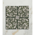 Four square dark green studio assisi ceramic tiles with intricate white floral and vine patterns for decorative use