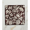 Studio Assisi Red ceramic square tile with deep burgundy glaze and intricate white floral pattern of leaves and vines