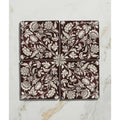 Four square studio assisi red ceramic tiles with intricate white floral and vine patterns on deep burgundy background