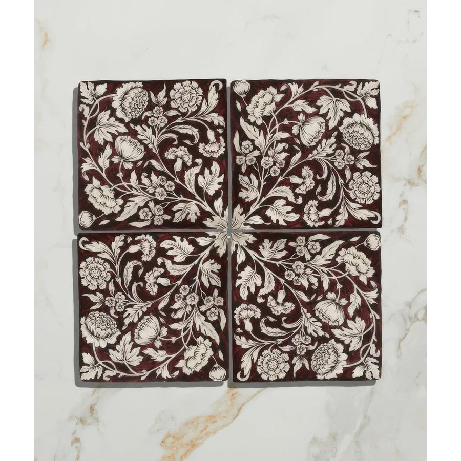 Four square studio assisi red ceramic tiles with intricate white floral and vine patterns on deep burgundy background