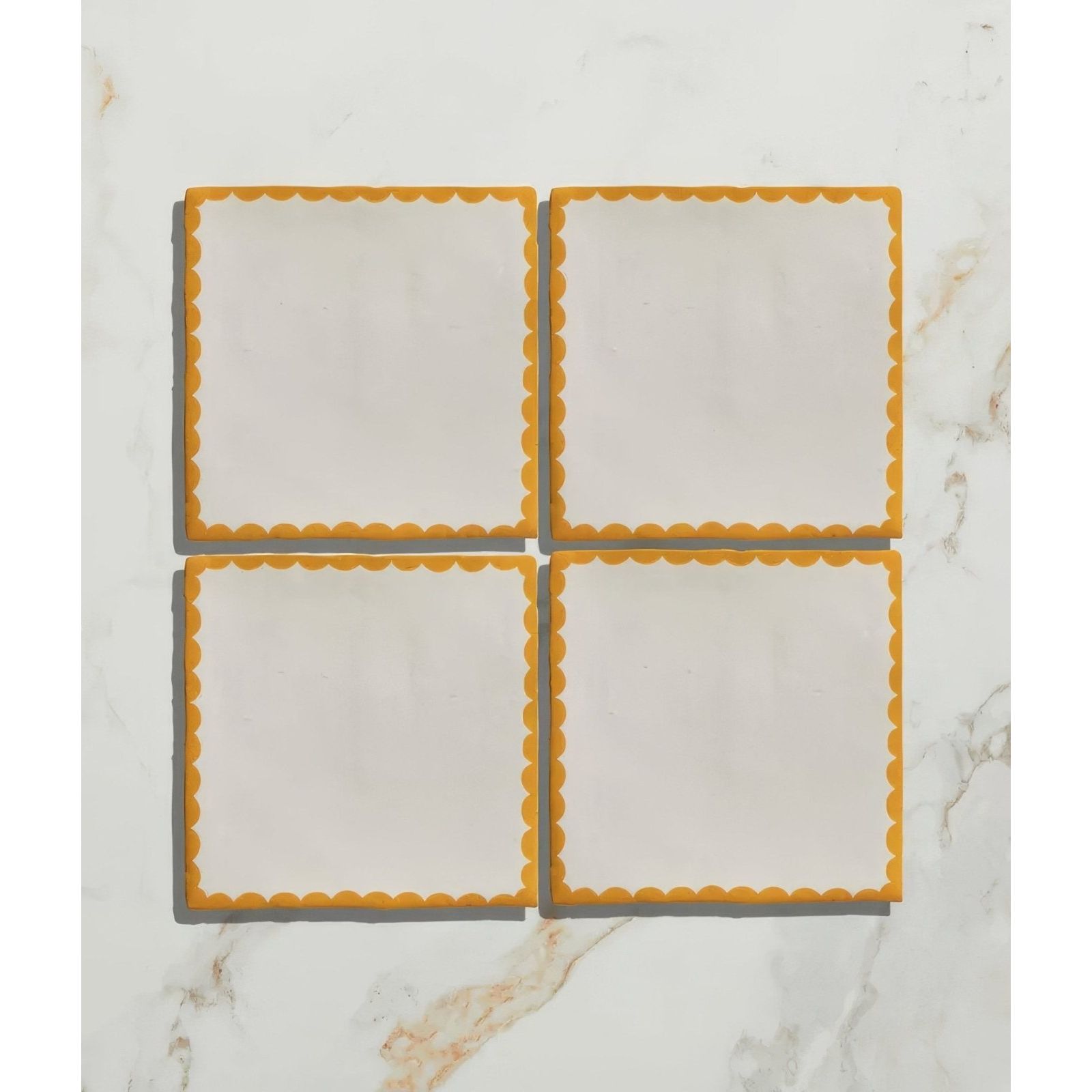 Set of four studio bobbin ceramic summer coasters with white centers and vibrant orange scalloped edges