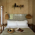 Studio cosmos midnight ceramic tea set displayed with white pillow and olive green textured blanket on woven wicker baskets