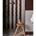 A white ceramic pump bottle with black leaf design labeled magnified sits beside an orange loofah on a wooden stool