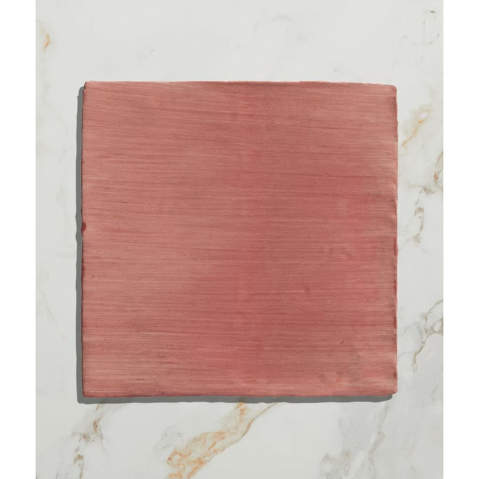 A square terracotta-colored handpainted ceramic tile with subtle horizontal texture from studio jamboree coral field