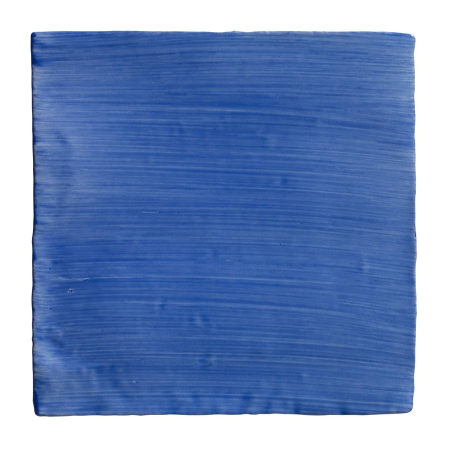 A square ceramic tile with vibrant blue glaze and horizontal brushstroke texture from Studio Jamboree Handpainted Greek Blue Field