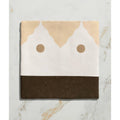 A folded beige white and brown patterned textile with a minimalist face design for studio minaret brown dot ceramic