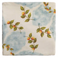 A ceramic tile from Studio Nonna’s Kitchen Nuvola Arancio with blue white marbled background and orange fruit branches
