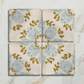 Four square ceramic tiles from Studio Nonna’s kitchen Nuvola Arancio with hand-painted green leaves and orange fruits