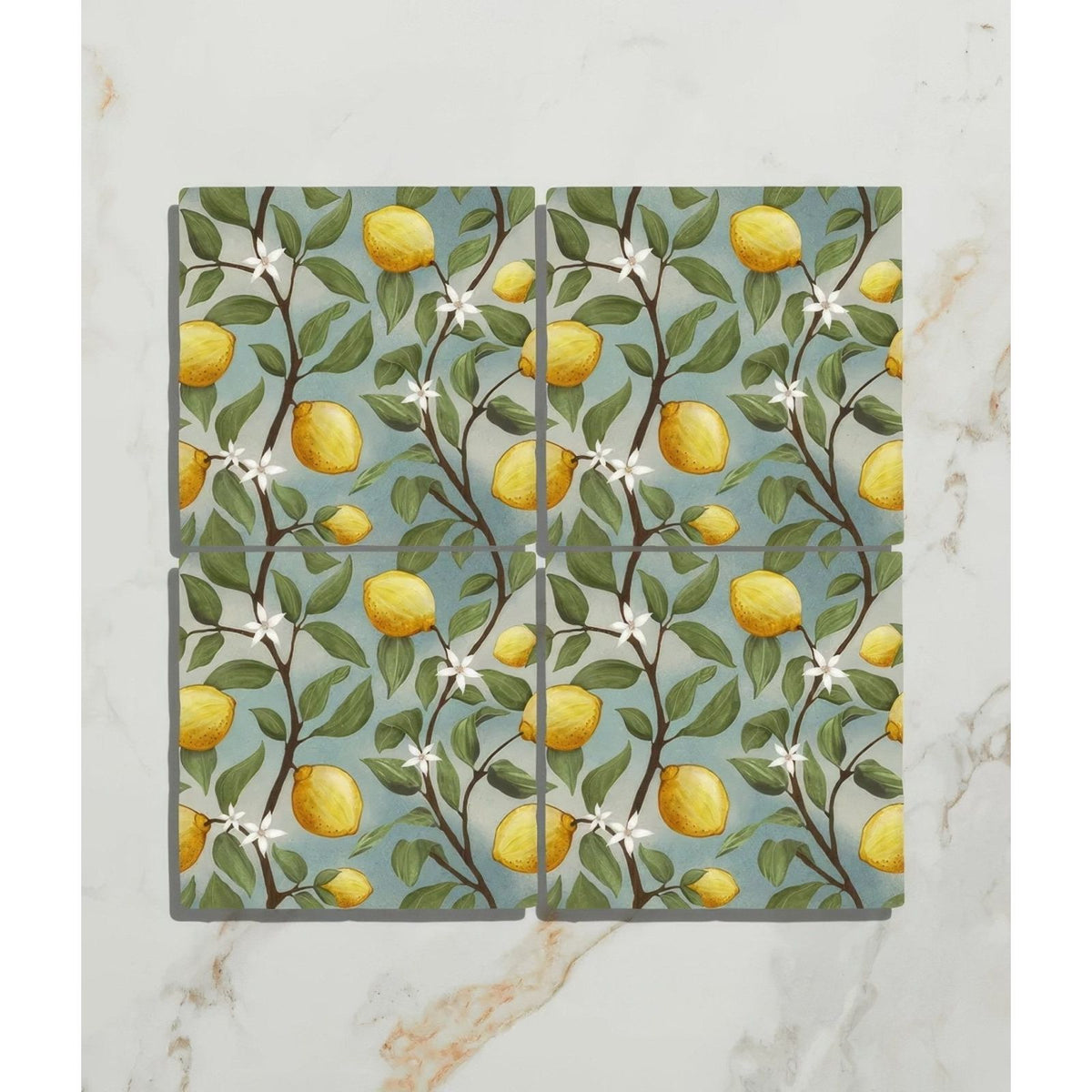 Set of four Studio Nonna ceramic coasters with vibrant lemon tree design on soft blue background for kitchen use