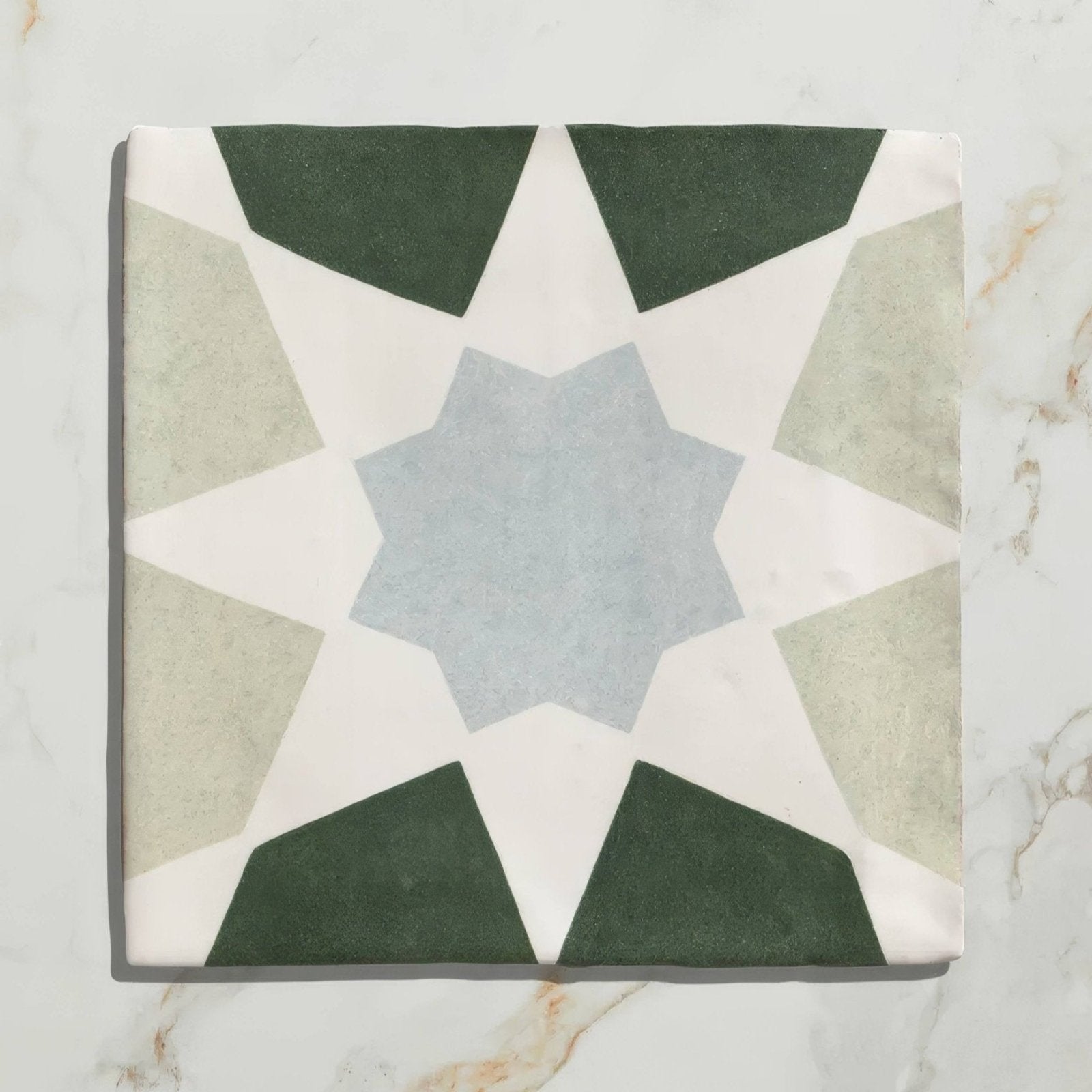 Square ceramic tile with geometric star pattern in muted green beige and light blue tones from Studio Souk Blue Star Ceramic